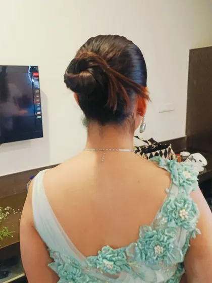 A modern and chic twisted updo, perfect for a cocktail party or reception. This hairstyle is sleek and keeps the hair neatly off the shoulders to showcase the outfit's neckline.