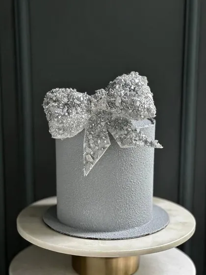 A stunning grey cake with a sparkling, crystal-like sugar bow. This is a glamorous and modern design, perfect for a milestone birthday or a chic event.