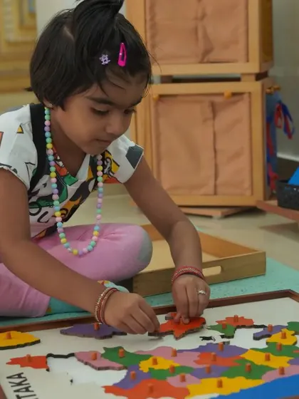 The puzzle maps are a favorite material in the cultural area. As this child assembles the map of Karnataka, she is learning the names and shapes of the districts, developing fine motor skills, and building a foundation for geography.