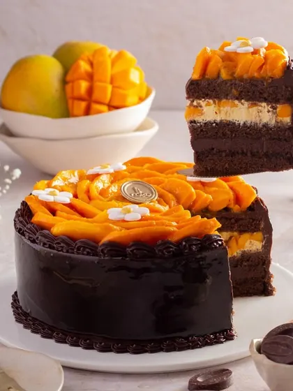 A slice of our Chocolate Mango Cake being lifted from the whole cake, showcasing its moist crumb and layers of mango cream. It's a tempting preview of this unique seasonal dessert.