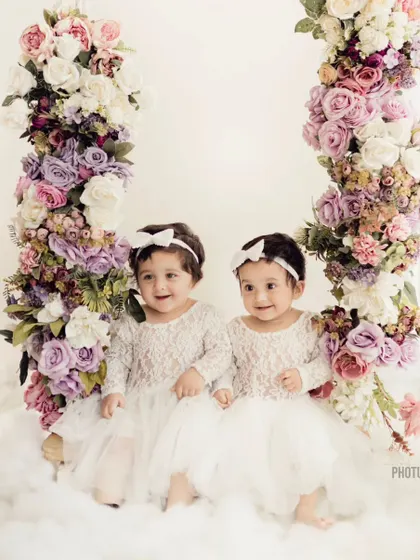 Twin sisters sitting together on the floral swing. Capturing the bond between siblings, especially twins, is one of our favorite things to do.