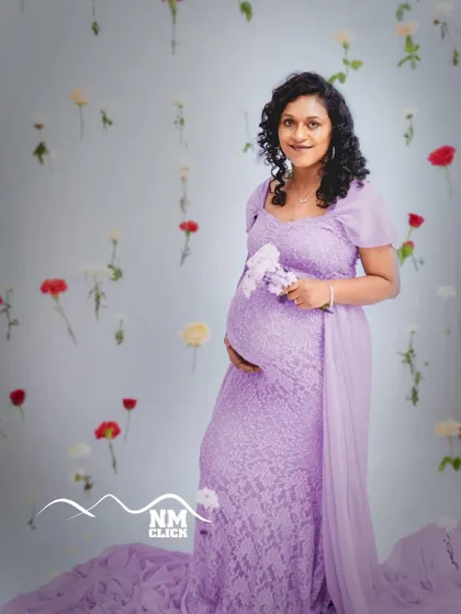 Our 'life-in-bloom' theme is a favorite among expecting mothers. Here, we used a backdrop of delicate hanging flowers to create a dreamy and ethereal portrait, perfectly complementing the soft lavender lace gown from our studio collection.