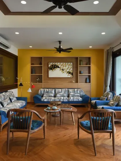The drawing room in the Ashraya Residence features expansive glass panels that connect it seamlessly to the verdant garden. This transforms the garden into a versatile extension of the living space, ideal for hosting gatherings.