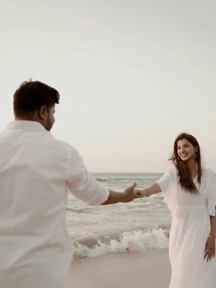 A playful and candid moment by the sea. His smile as he leads her shows the fun and joy in their relationship.