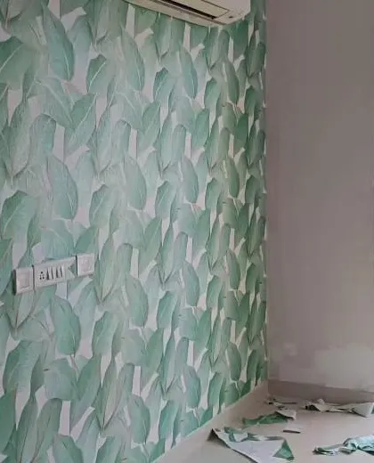Another view of a green leaf wallpaper installation in progress, showing the fresh and vibrant impact it has on the room.