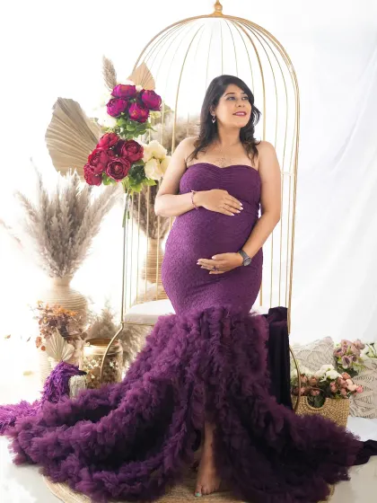 A stunning solo portrait of a mom-to-be in a purple mermaid gown. The soft lighting and dreamy setup create a truly magical atmosphere.