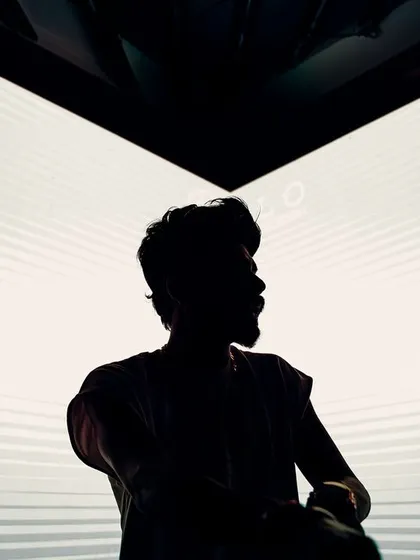 A silhouette against the club's visuals. This artistic shot represents how the DJ becomes a part of the venue's overall sensory experience, guiding the night with sound.