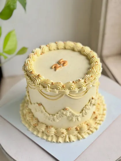 Golden hour, but make it cake. This vintage design in a warm yellow hue features intricate piping, scalloped edges, and tiny gold pearls for a touch of shimmer.