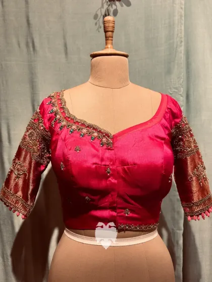 A hot pink silk blouse with a beautifully embellished neckline and linear embroidery on the sleeves.