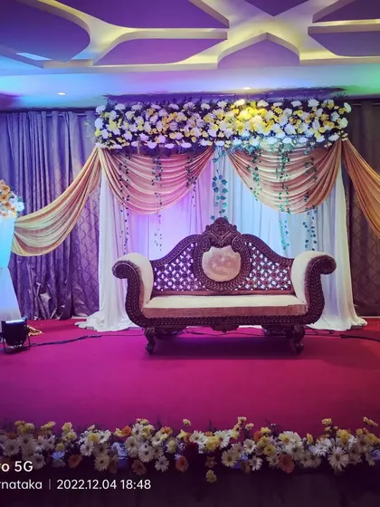 A clear, well-lit view of a classic reception stage. The gold draping and floral cornice create a warm and inviting atmosphere, perfect for an evening celebration in a function hall.