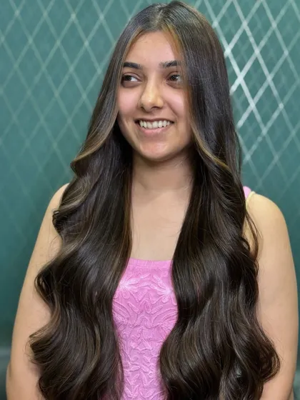 A happy client showing off her new look. The face-framing highlights brighten her complexion, while the deep brown base keeps the style looking rich and healthy.