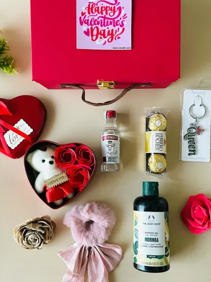 This Valentine's hamper for her comes in a red suitcase box and is filled with a Body Shop shower gel, a "Queen" keychain, Ferrero Rocher, and a miniature drink.