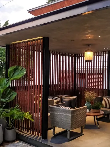 A corner of the Chhabria's Terrace featuring comfortable wicker armchairs and vertical wooden slats that provide privacy while allowing for airflow and light play.
