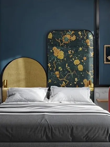 We designed this bedroom with a bold, artistic flair. It features a custom asymmetrical headboard with gold and floral patterns, paired with a deep blue wall and a unique pink armchair, creating a vibrant and eclectic space.