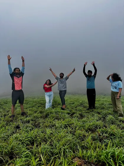 A group of friends celebrating at the top of Gangadikal, with the mist all around them.