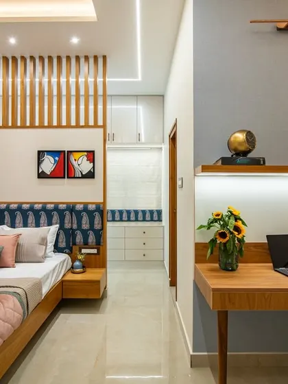 The "after" shot of a bedroom transformation, now featuring an Indian contemporary design. A paisley-patterned headboard is paired with a wooden slat partition, and a sleek floating desk creates a functional workspace.
