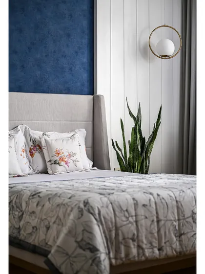 A minimalist pendant light and a snake plant add a touch of modern style and greenery to the serene guest bedroom.