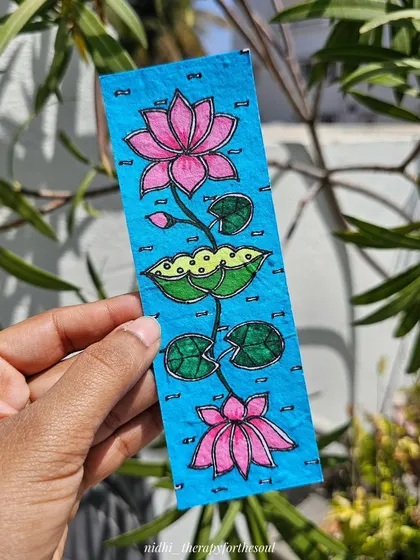 A close-up of a Madhubani bookmark featuring a lotus design on bright blue seed paper. These are free with orders over a certain value.