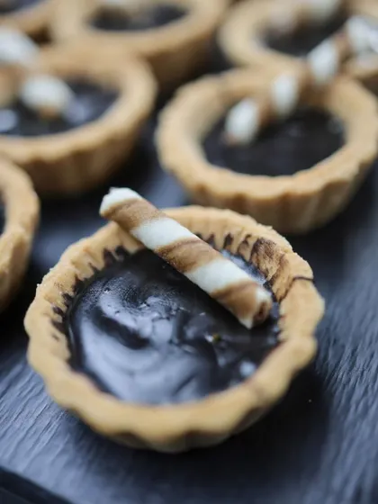 A close-up of our mini chocolate tarts, topped with a wafer roll. These single-bite desserts are rich, decadent, and perfect for a pass-around service.