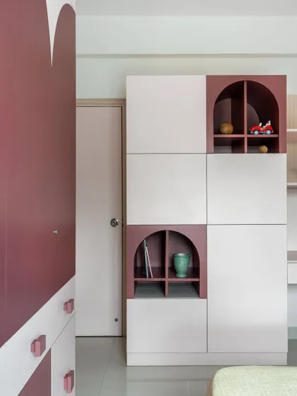The custom storage unit in this room features a playful mix of closed cabinets and arched open niches in a contrasting color, perfect for displaying toys and treasures.