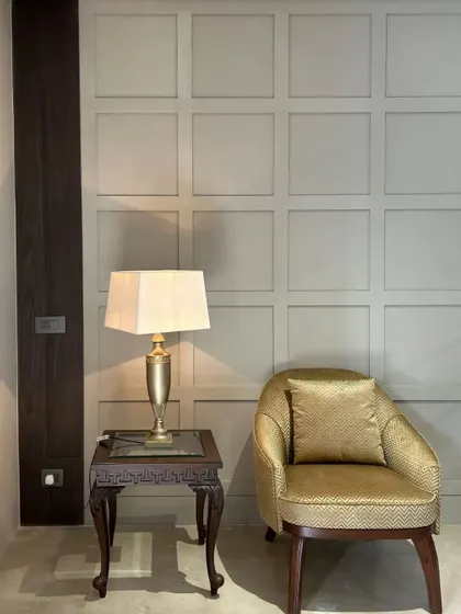 A custom armchair upholstered in a golden chevron-patterned fabric brings warmth and personality to this reading corner. The piece is paired with a classic carved side table, showcasing our ability to blend different aesthetics into a cohesive whole.
