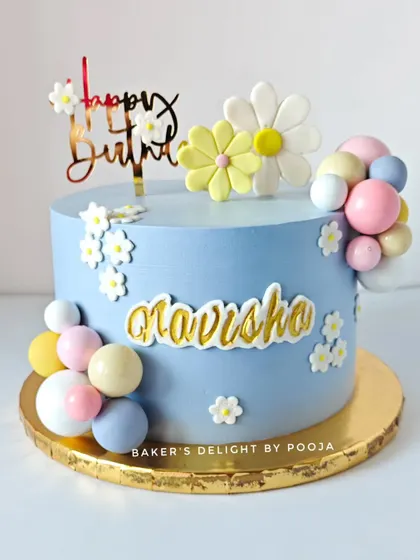 A beautiful birthday cake in soft pastel blue, decorated with daisies and colorful chocolate spheres. This design is sweet, cheerful, and perfect for a 9th birthday.