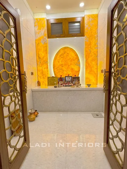 Another perspective looking into the puja room, showcasing the intricate details of the custom doors and the warm, inviting glow from within.