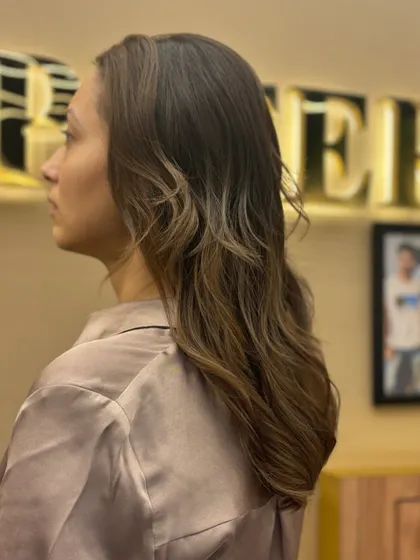 A side profile of a client with her new hair color. The gentle waves and highlights create a look of effortless elegance.