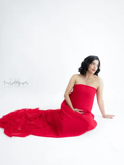 A simple and elegant portrait in a flowing red gown. The clean white background makes the vibrant color pop, creating a striking image.