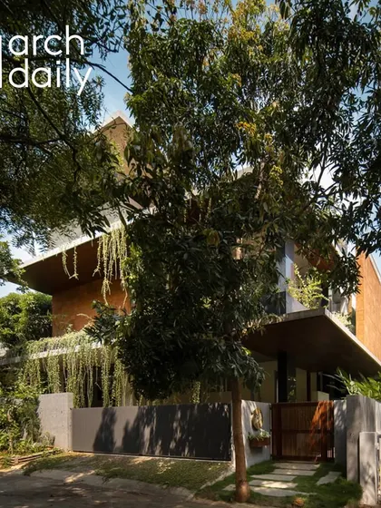 The 'House of Greens' featured on ArchDaily, seen from the street with the preserved mango tree in the foreground.