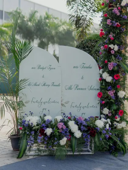 A unique double welcome sign for a wedding celebrating the union of two families, beautifully framed with flowers.