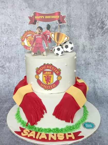 A cake for a true Manchester United fan. This design features the team's logo, a team scarf, and a custom topper of the birthday boy in his favorite player's jersey.