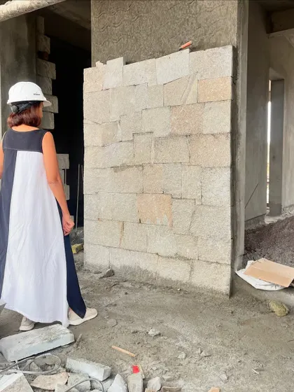 An architect inspects a mock-up of a random rubble stone wall on site. This hands-on approach ensures the final quality of craftsmanship meets our exacting standards.