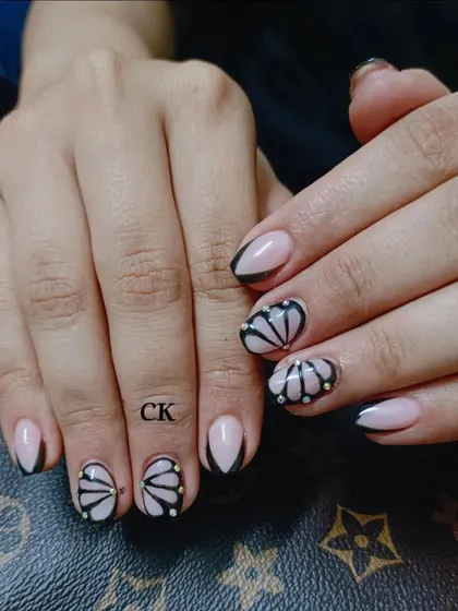 A unique design with a black French tip and a hand-painted shell-like pattern with pearl accents.