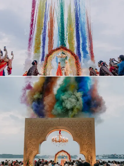 Two perspectives of the spectacular rainbow smoke display during Maheswari and Basu's varmala, showcasing the grandeur of their lakeside wedding.