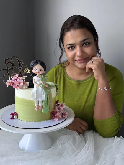 A tribute to timeless elegance. This 50th birthday cake features a handcrafted figurine of a woman in a beautiful white suit with a gorgeous green dupatta.