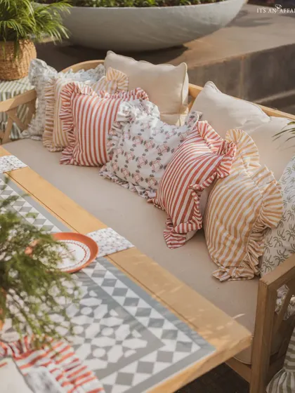 A close-up of the ruffled and patterned cushions that add softness and a touch of country charm to the wooden benches.