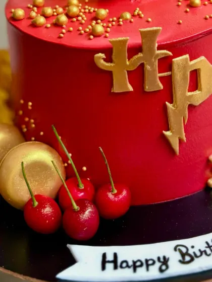 A close-up of the golden HP logo and fresh cherries on this magical Harry Potter cake.