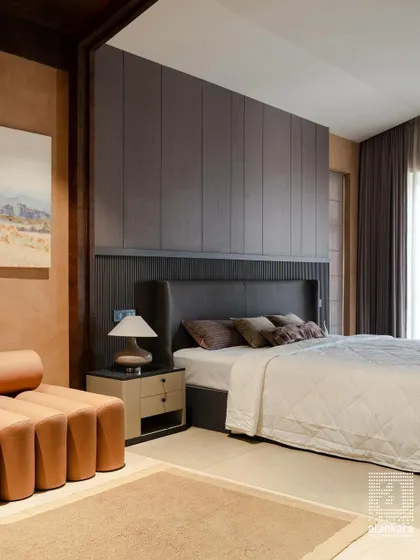 A wider view of the modern bedroom, showing how the custom headboard and paneled wall integrate with other elements like the unique terracotta-colored sofa and soft, neutral-toned textiles.