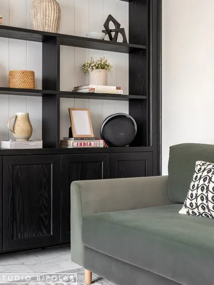 In the Sunlit Serenity living room, a deep green sofa sits beside a custom black display unit. We love using built-in furniture to create a sense of permanence and provide beautifully styled storage.