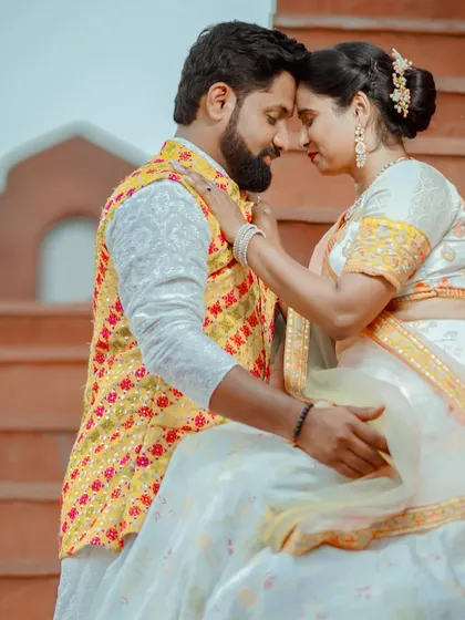 An intimate moment during a pre-wedding shoot. The couple is dressed in vibrant traditional attire, and the warm editing enhances the romantic mood.
