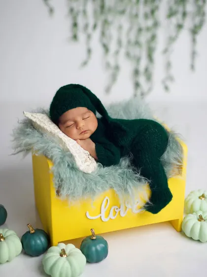 The same setup, but with the baby in a cute, matching green knit outfit and sleepy hat.