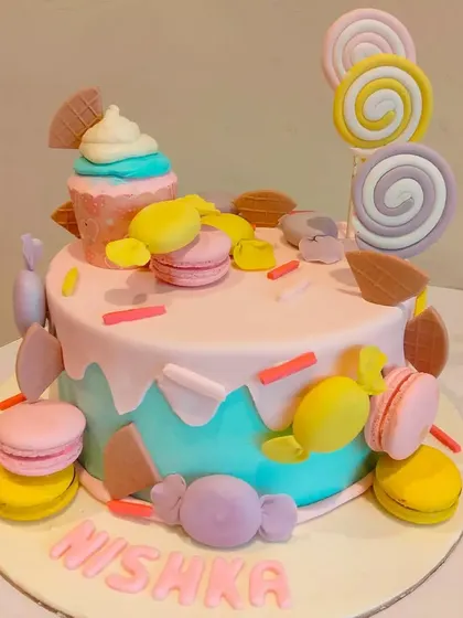 A pastel-colored candy-themed cake decorated with macarons, lollipops, and other sweet treats. It's a dream cake for anyone with a sweet tooth.