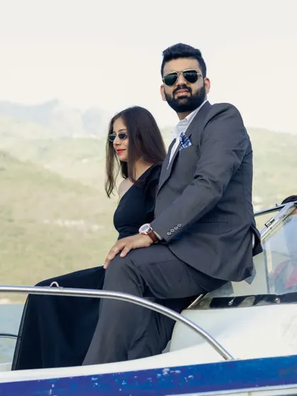 A cool, magazine-style shot of the couple posing on the front of the speedboat, exuding confidence and style.