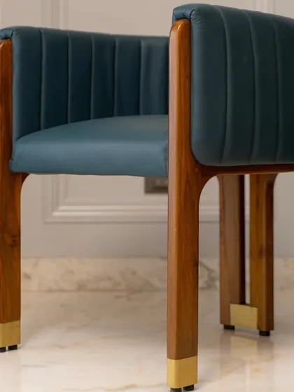 An artistic accent chair made from teak wood and leather, with brass-capped legs. I design chairs like these to be the crown jewel of a living room, reflecting a client's personal style.