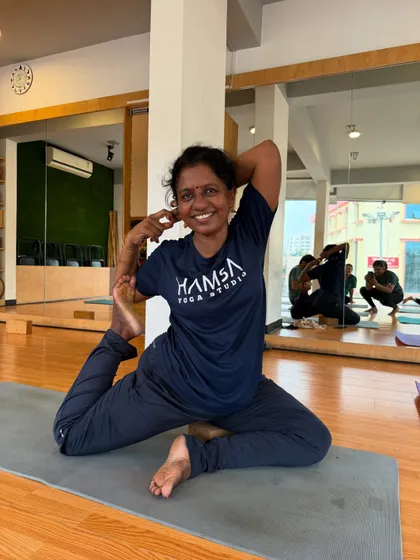 A smiling student in Eka Pada Rajakapotasana (One-Legged King Pigeon Pose), a deep hip and heart-opening pose.