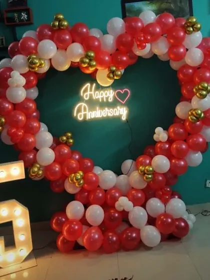 A heart-shaped balloon arch in red, white, and gold for a 5th-anniversary celebration, complete with a light-up number "5".