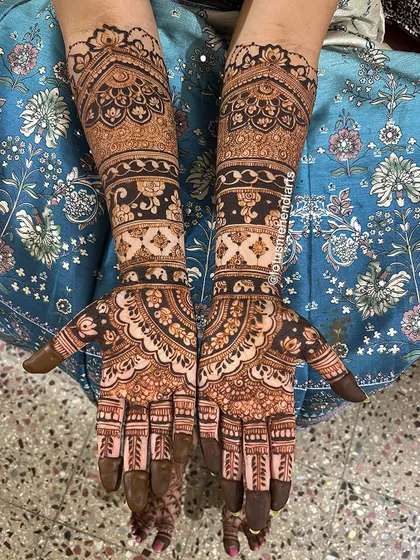 A top-down view of the completed bridal mehendi, showing the full, symmetrical design on both hands.