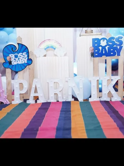 A detail shot of the props for a Boss Baby party, including the light-up name sign and themed cutouts.