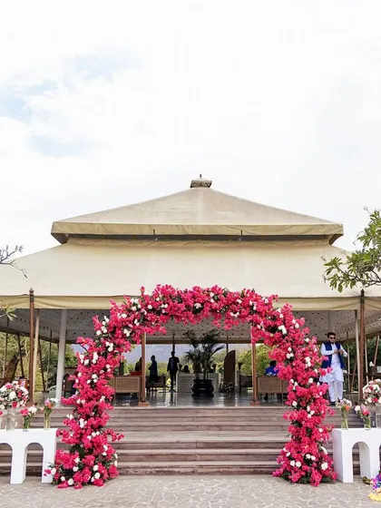A beautiful floral arch of vibrant bougainvillea frames the entrance to this daytime event at Alila Fort Bishangarh, perfectly complementing the venue's natural beauty.